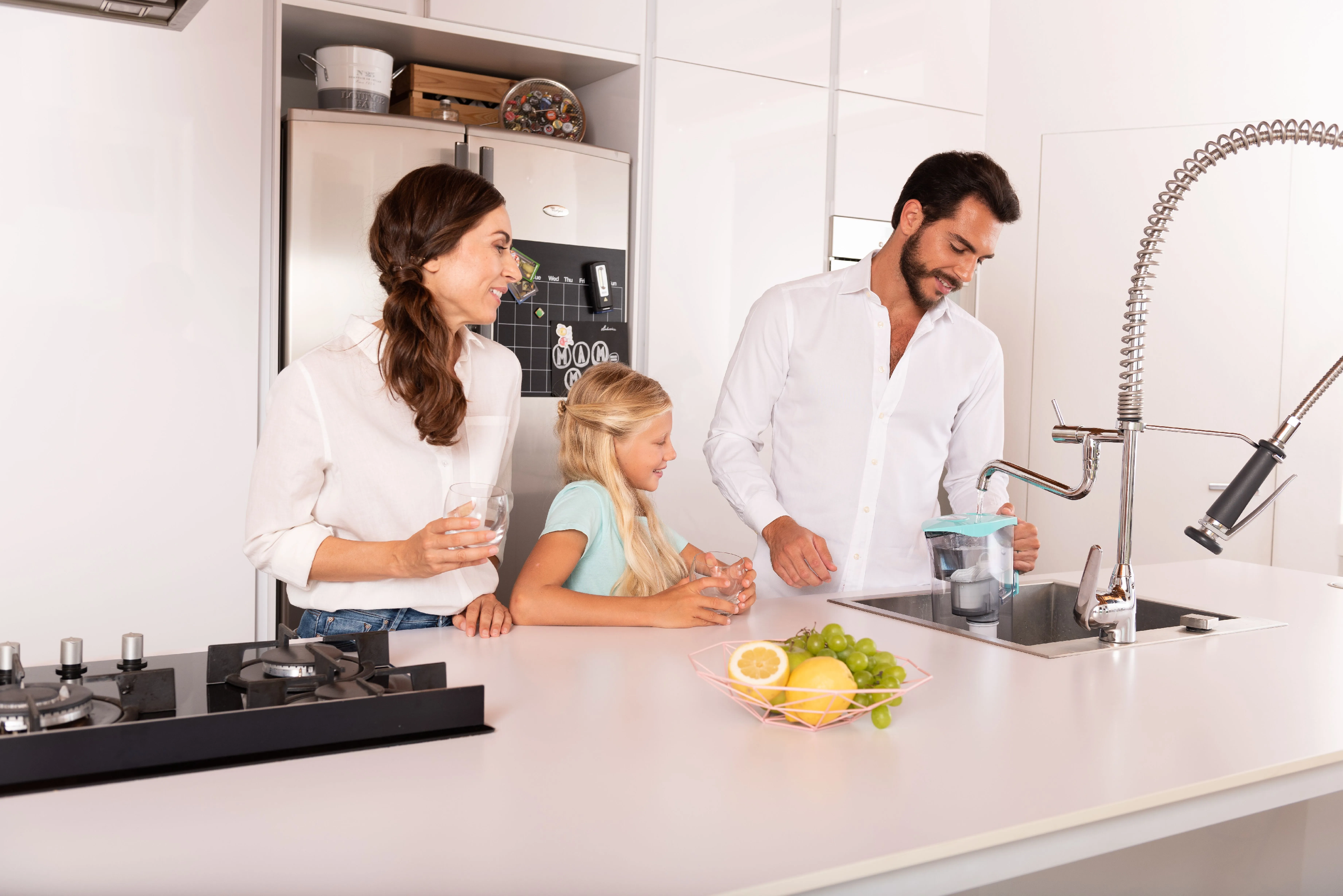 Rodina si užívá čistou vodu z konvice LAICA MikroPLASTIK-STOP v moderní kuchyni